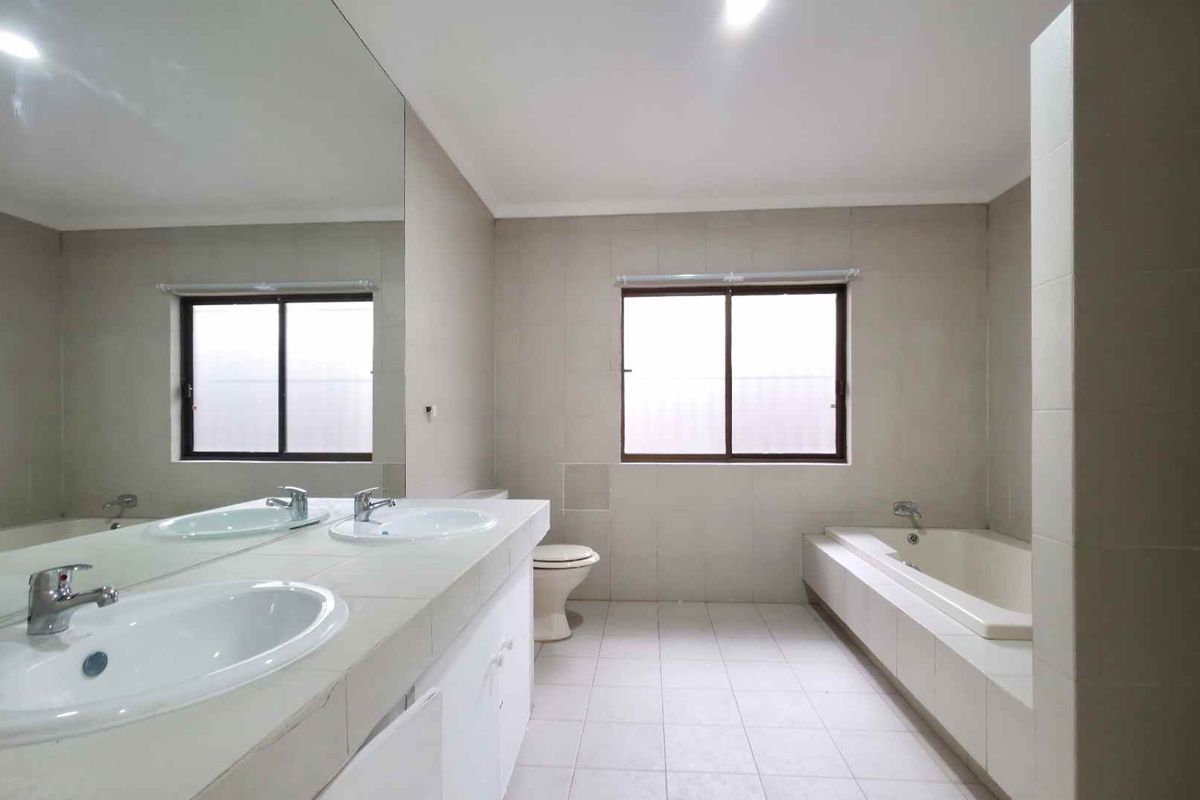 Spacious bathroom featuring a double vanity with integrated sinks, a large wall-mounted mirror, a built-in bathtub, and tiled flooring.