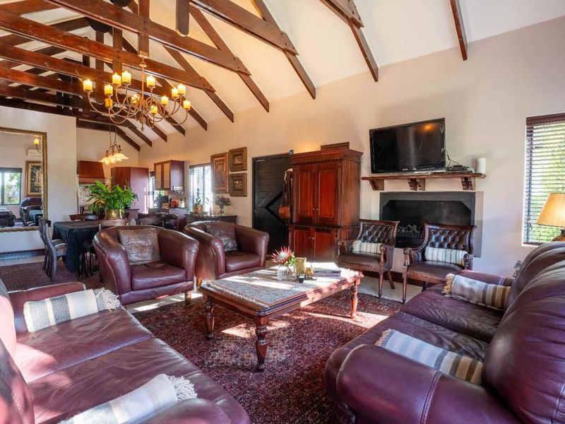 Spacious open-plan living area featuring a vaulted ceiling with exposed timber trusses, a built-in fireplace, and warm, traditional finishes.