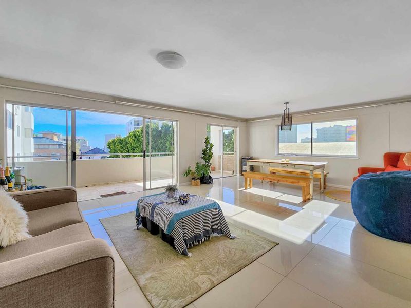 Spacious open-plan living and dining area featuring large sliding glass doors that open onto a balcony, providing ample natural light and a bright atmosphere.