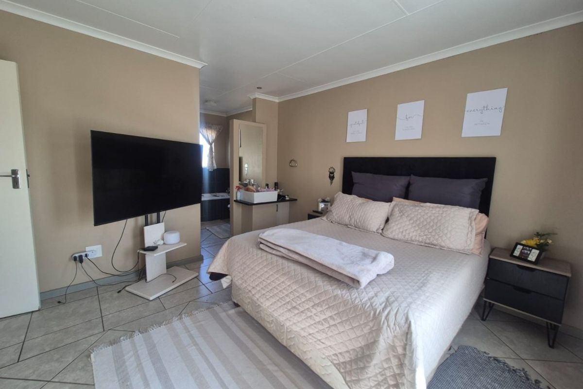 A bedroom featuring tiled flooring, coved ceilings, and an integrated vanity area leading to an en-suite bathroom.