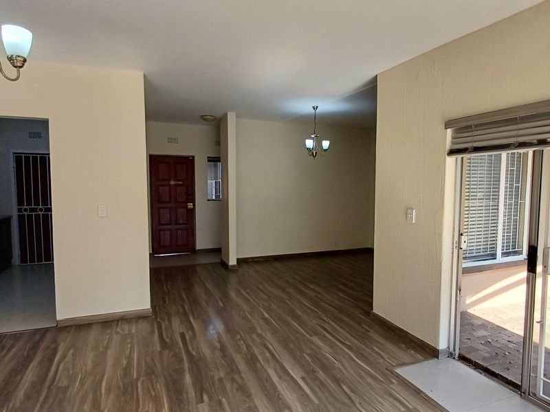 Spacious open-plan living area featuring modern laminate flooring, neutral walls, and direct access to an outdoor patio through sliding glass doors.