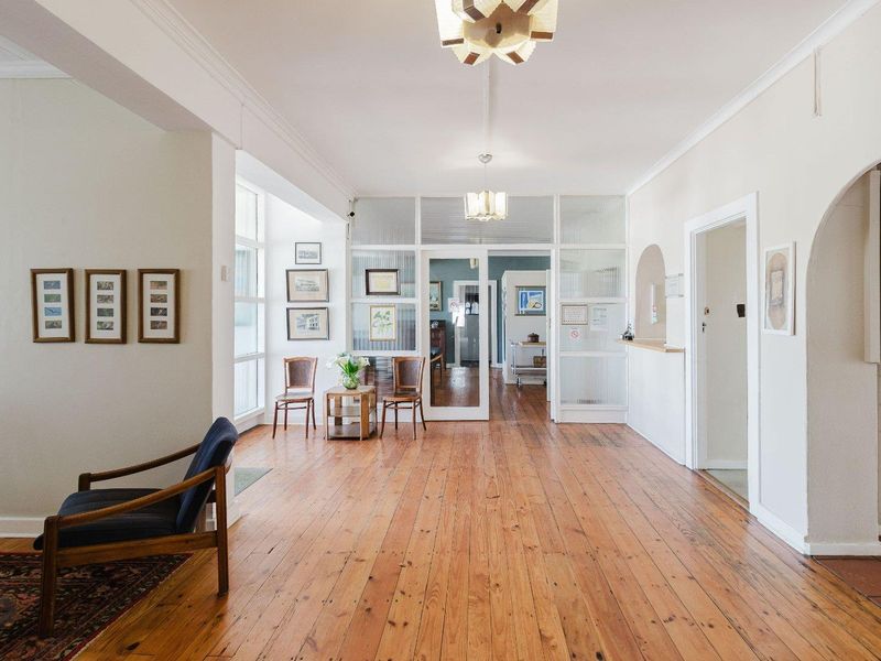 Spacious entrance area featuring polished timber flooring, a glass panel partition, and a reception counter, creating a welcoming and professional business reception space.