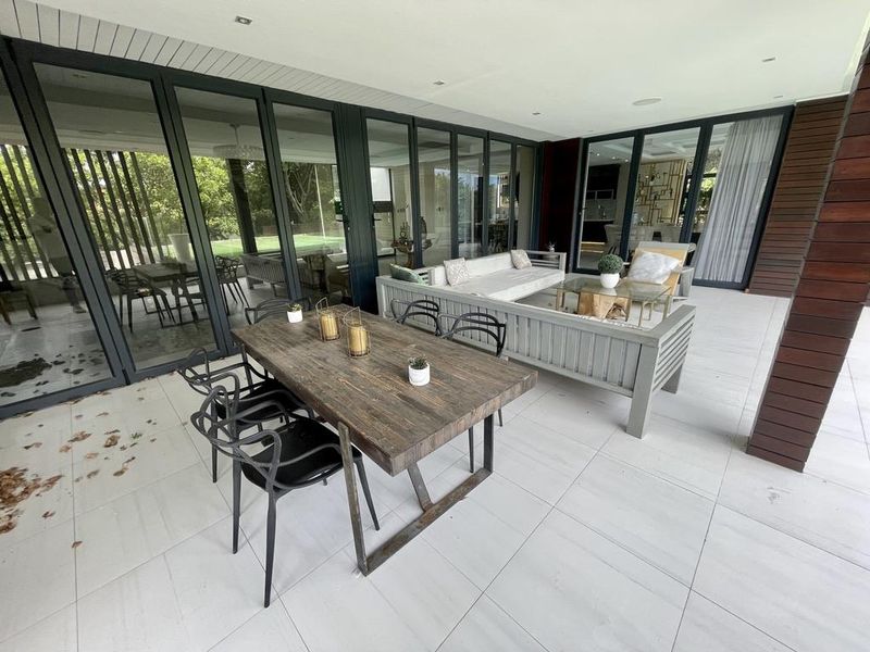 A spacious covered patio featuring large glass sliding doors, modern tiled flooring, and timber wall cladding, perfect for outdoor entertaining.