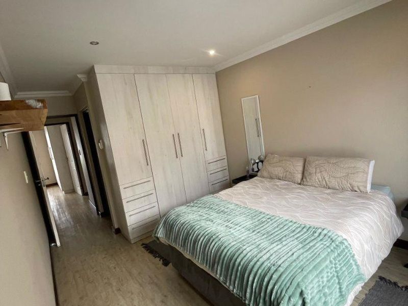 A well-maintained bedroom featuring light-toned laminate flooring, built-in cupboards, and recessed ceiling lighting.