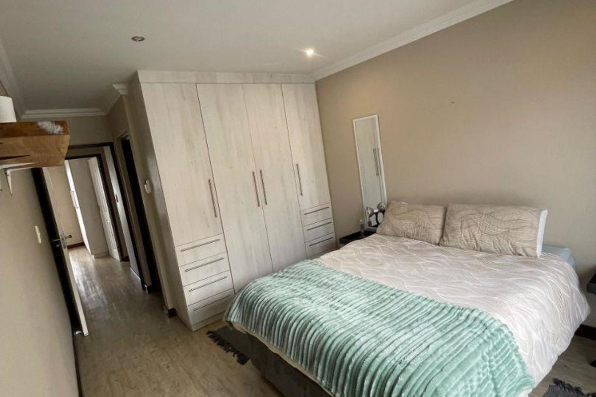 A well-maintained bedroom featuring light-toned laminate flooring, built-in cupboards, and recessed ceiling lighting.