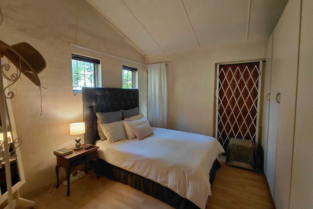 A cozy bedroom featuring built-in wardrobes, laminate flooring, and a security gate on the door, providing a functional and secure living space.