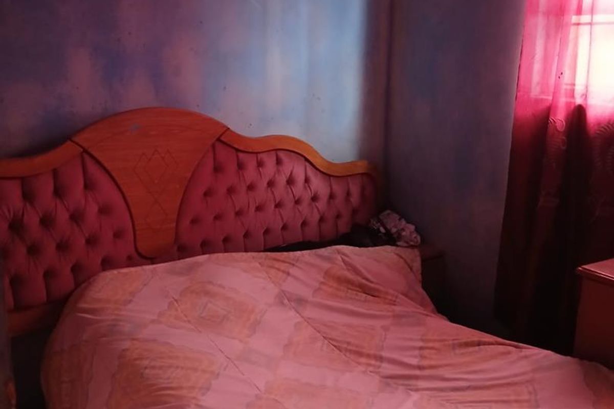 A bedroom featuring a window with red curtains and blue textured walls, requiring cosmetic updates to improve the overall aesthetic.