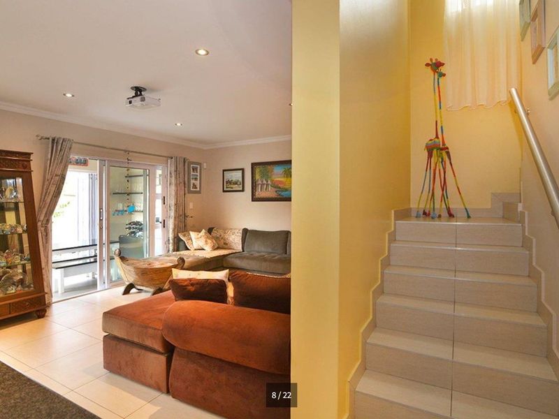 Open plan living area featuring tiled flooring, recessed lighting, and a staircase with a metal handrail leading to the upper level.