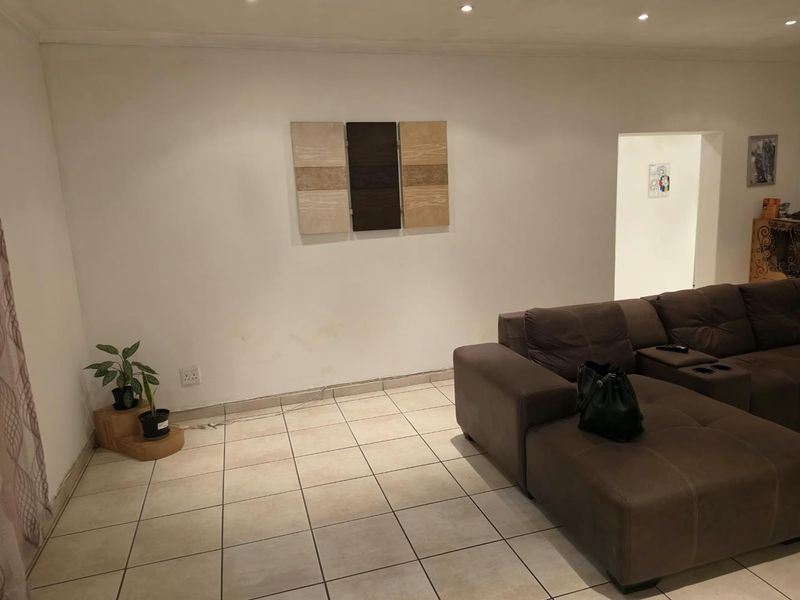 A living room area featuring neutral ceramic floor tiles and recessed ceiling lighting, providing a functional base for interior design updates.
