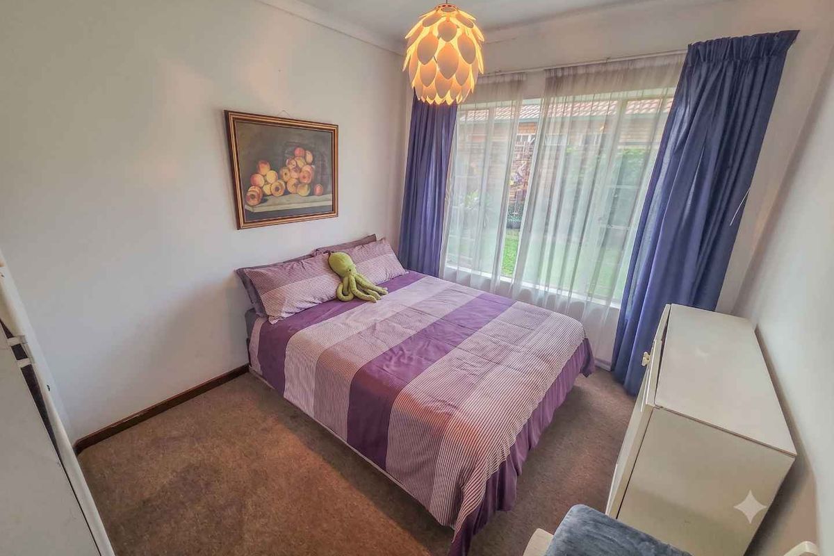 A standard bedroom featuring carpeted flooring, a large window with curtains, and built-in cupboard space.