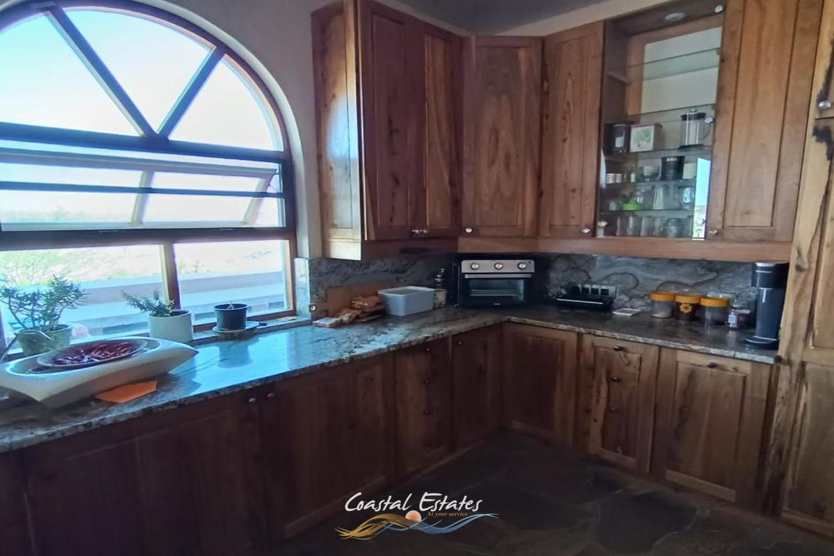A kitchen featuring solid wood cabinetry, granite countertops, and a distinctive arched window that provides natural light.
