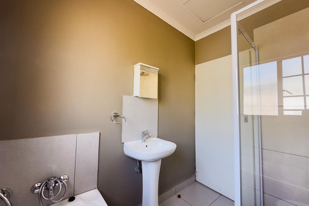 A functional bathroom featuring a pedestal basin, a separate shower enclosure with glass door, and a bathtub with chrome fixtures.