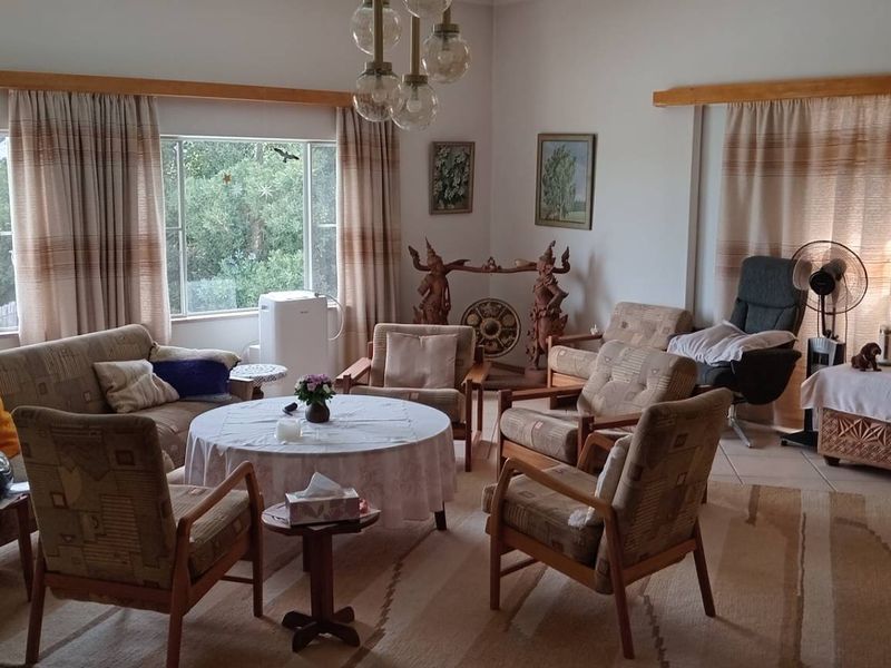 Spacious living room featuring large windows with timber pelmets and tiled flooring, offering a bright and comfortable area for relaxation.
