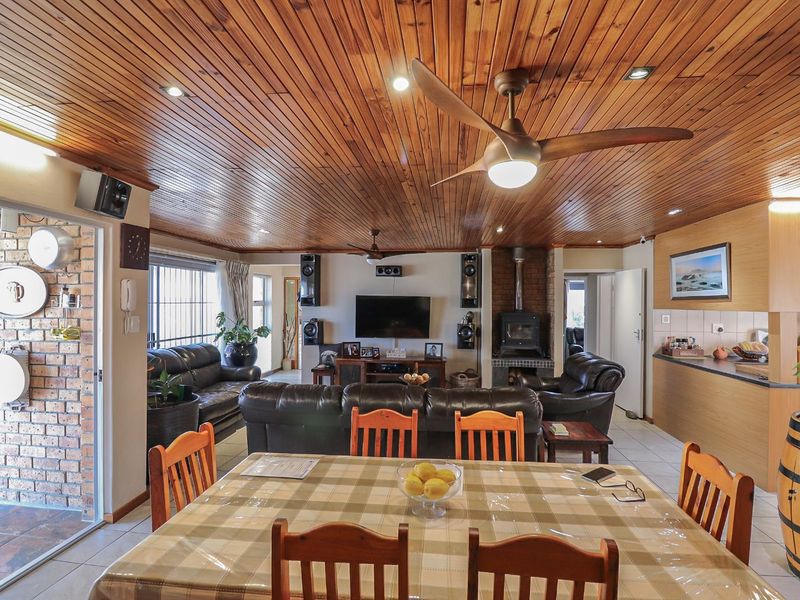 Spacious open-plan living and dining area featuring a timber-clad ceiling, wood-burning fireplace, and direct access to an outdoor patio.