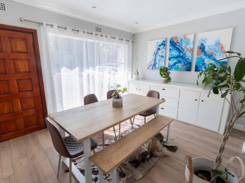 Bright dining area featuring wood-look tile flooring, built-in storage cabinetry, and a sliding glass door providing natural light.