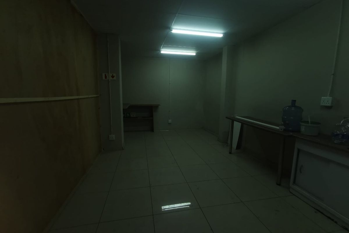 A dimly lit, vacant utility or storage space featuring tiled flooring and basic electrical infrastructure, suitable for various commercial storage or workspace applications.