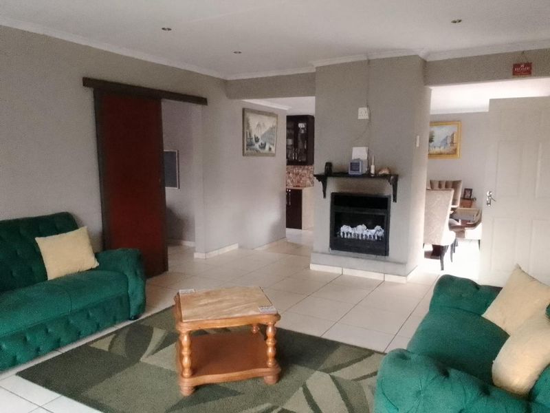 Open-plan living area featuring tiled flooring, a central built-in fireplace, and recessed lighting, providing a functional and connected space for relaxation and dining.