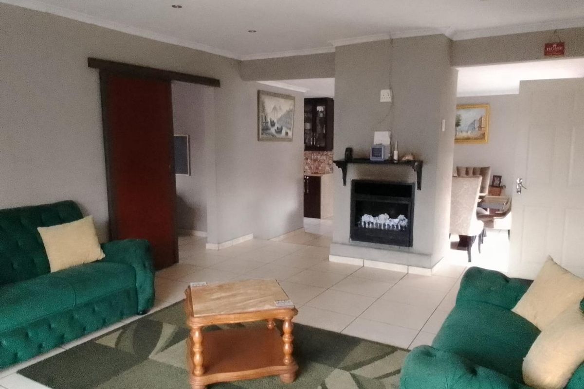 Open-plan living area featuring tiled flooring, a central built-in fireplace, and recessed lighting, providing a functional and connected space for relaxation and dining.