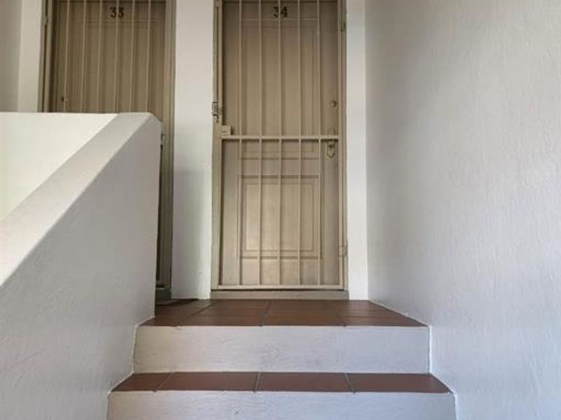 Entrance landing area featuring tiled stairs leading to apartment unit 34, secured with a metal security gate.