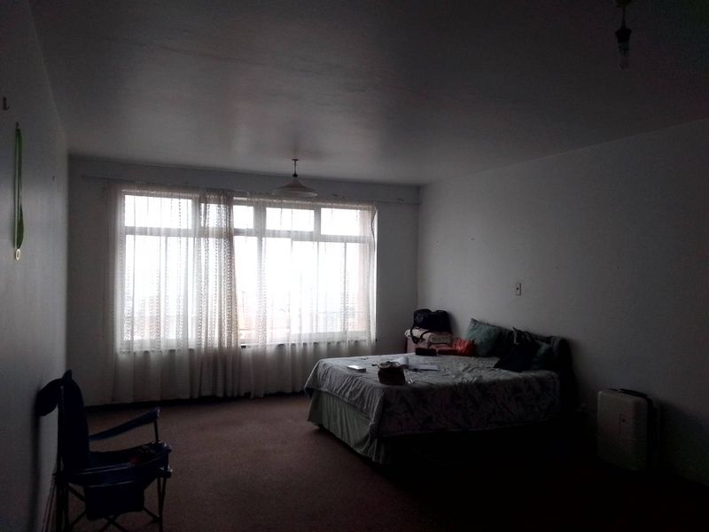 A spacious bedroom featuring large windows that allow for natural light and carpeted flooring throughout.