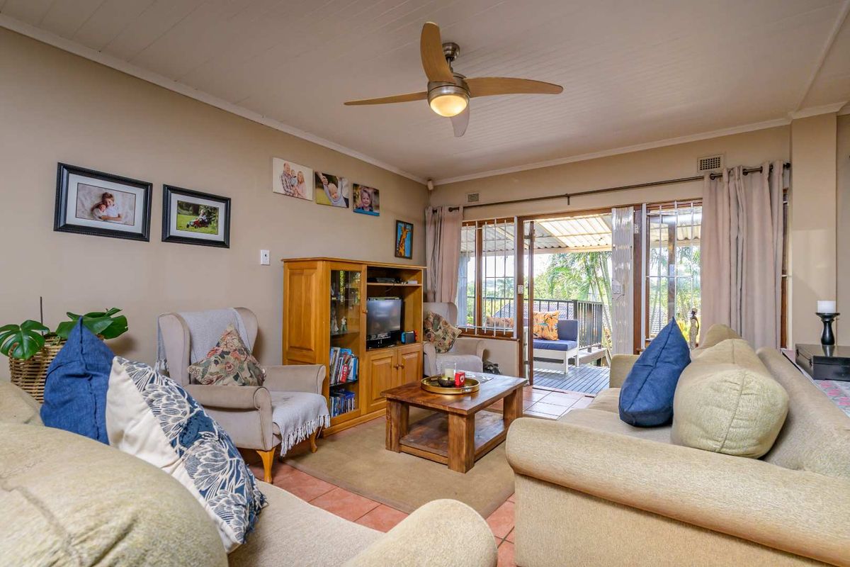 A comfortable living room featuring tiled flooring, a ceiling fan, and sliding glass doors that open onto an outdoor patio area.