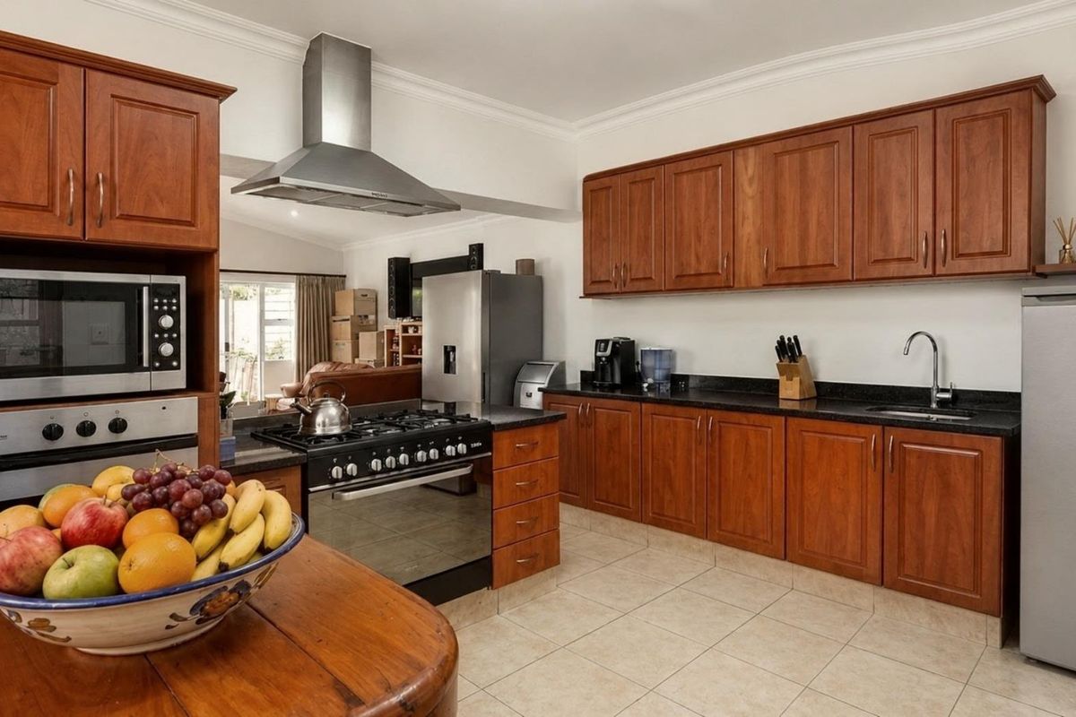 A functional kitchen featuring wooden cabinetry, granite countertops, a gas stove with an extractor fan, and a built-in oven.