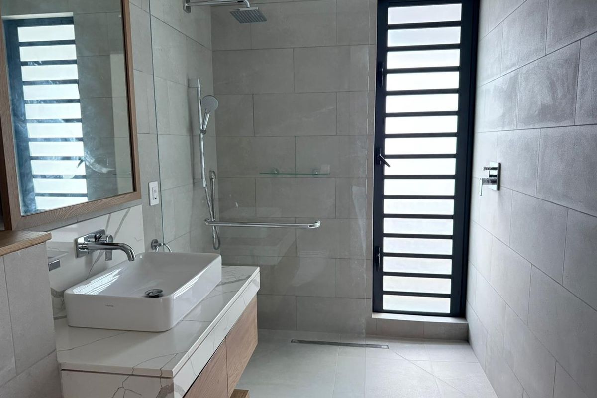 Modern bathroom featuring a floating vanity with marble-look countertop, vessel sink, walk-in shower with glass screen, and contemporary grey wall tiling.