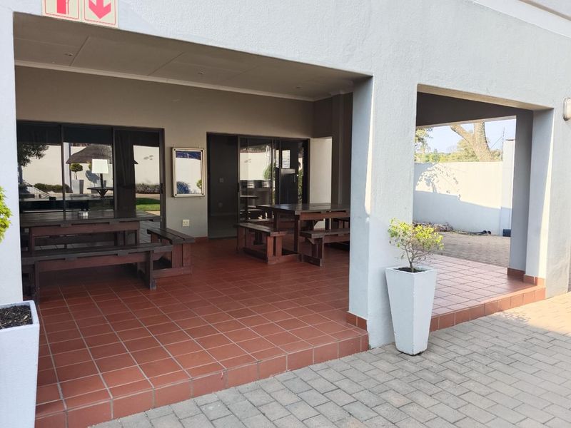A spacious covered patio area featuring tiled flooring and sliding glass doors, providing a seamless transition between indoor and outdoor living spaces.