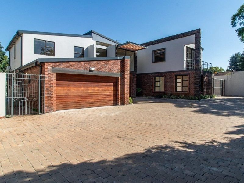 Modern double-story residence featuring a brick and plaster facade, a spacious paved driveway, and a secure timber-finish double garage.