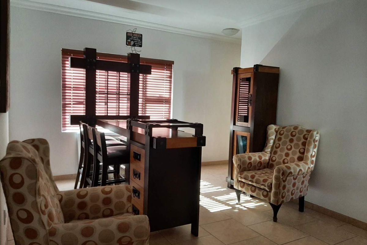 A living area featuring tiled flooring, neutral walls, and window blinds, providing a functional space with natural light.