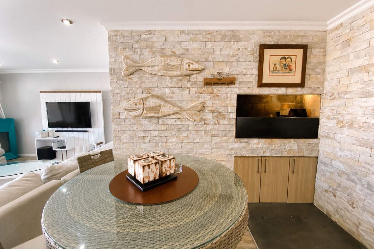 Spacious living area featuring a prominent stone-clad feature wall with a built-in indoor braai and modern recessed lighting.