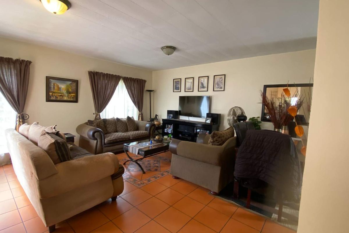 A spacious living room featuring terracotta floor tiles and neutral wall finishes, providing a comfortable and functional area for relaxation.