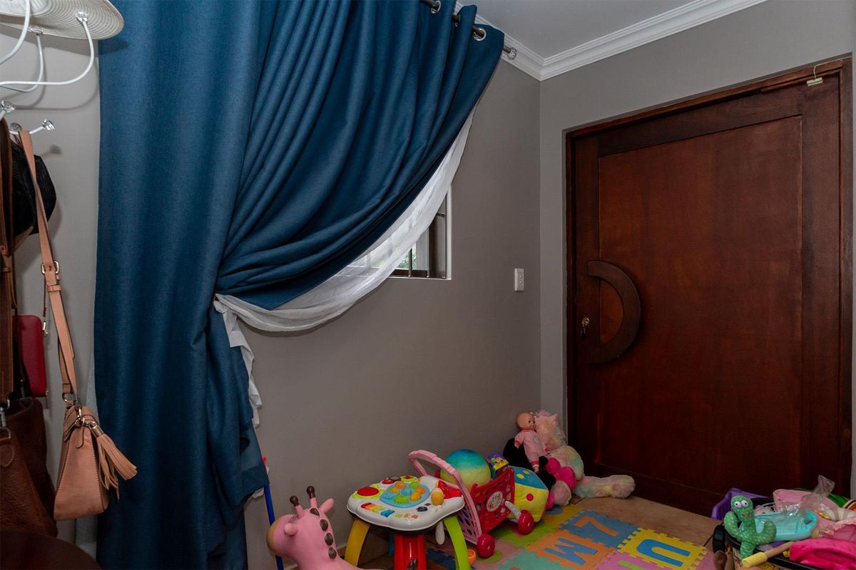 An interior view of a room featuring a solid timber door with a unique curved handle and window with blue curtains.