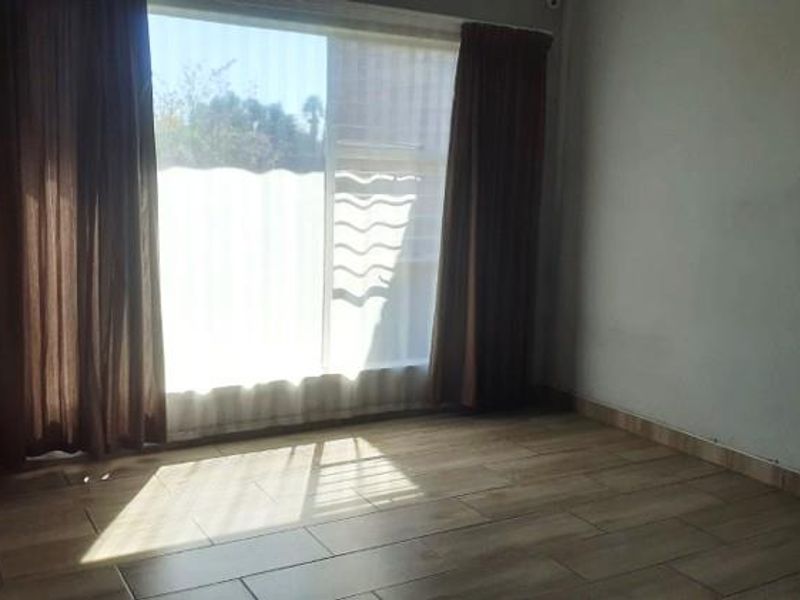 An empty bedroom featuring wood-look tile flooring and a large sliding glass door that provides natural light.