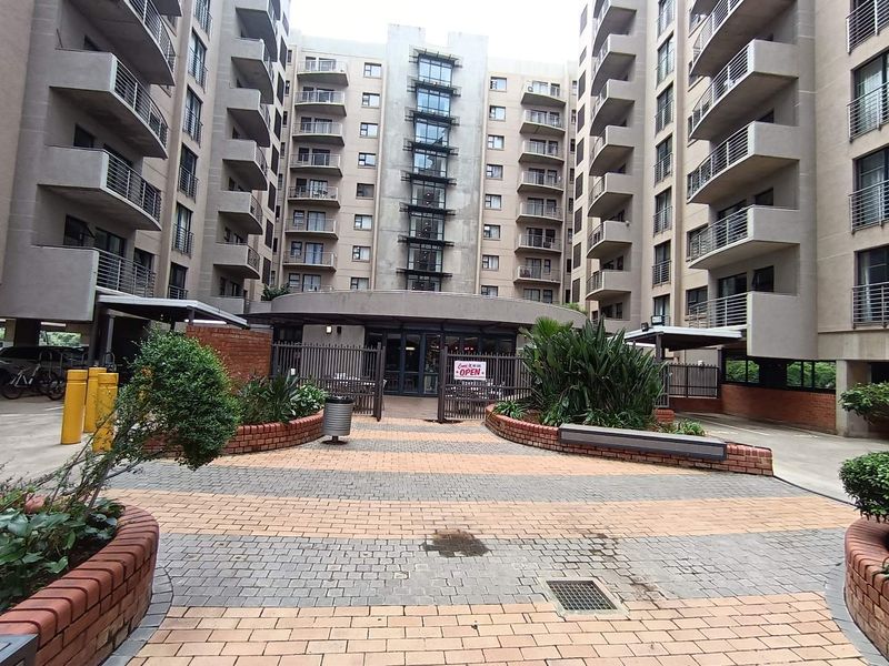 A view of the apartment complex courtyard featuring paved walkways, brick planter boxes, and multiple levels of balconies.