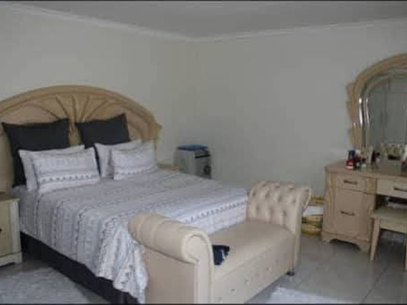 A bedroom featuring tiled flooring and neutral wall finishes, providing a functional space for rest.