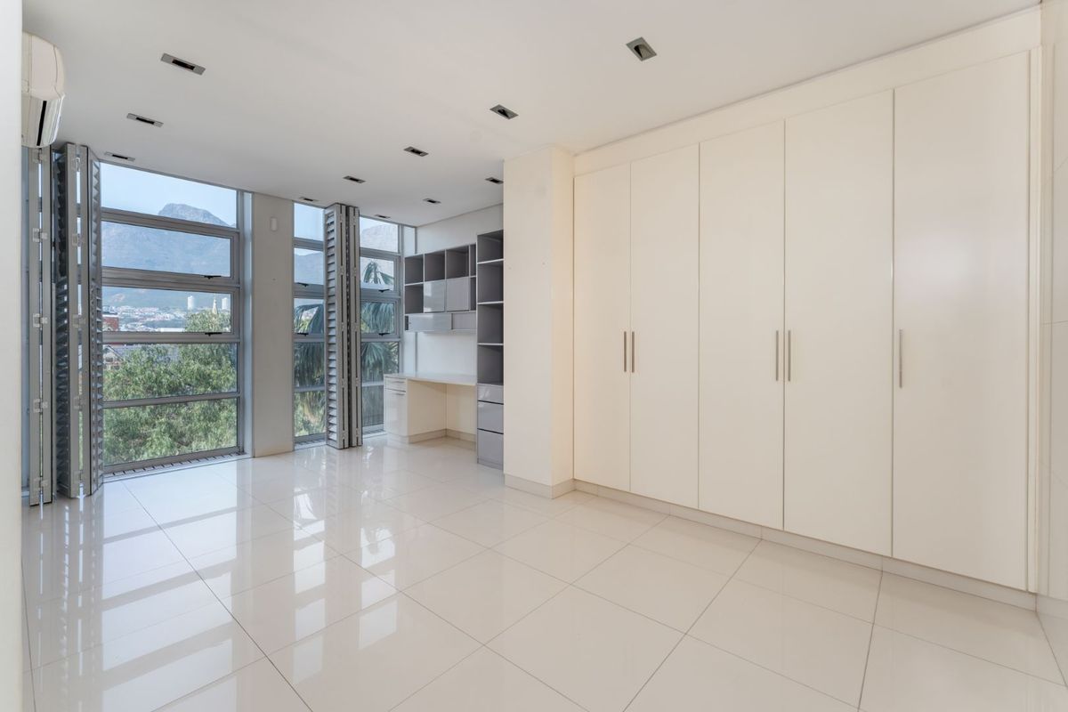 Spacious bedroom featuring high-gloss tiled floors, extensive built-in cabinetry, a dedicated desk area, and large windows offering scenic views.