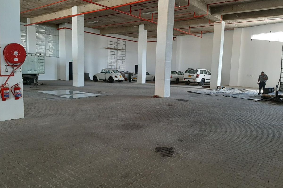 Spacious industrial garage area featuring exposed fire suppression systems, concrete structural columns, and durable paved flooring, suitable for storage or workshop use.