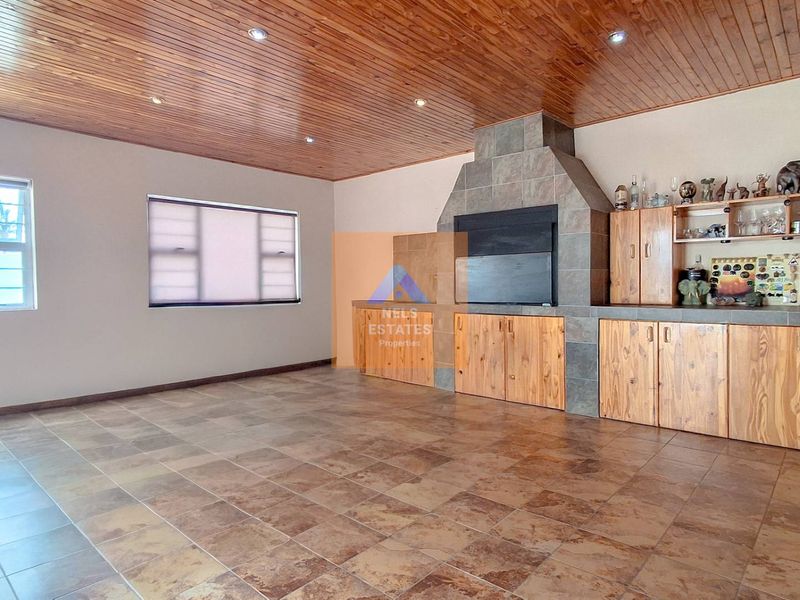 Spacious living area featuring a built-in fireplace, timber-clad ceiling, tiled flooring, and extensive built-in cabinetry for storage.