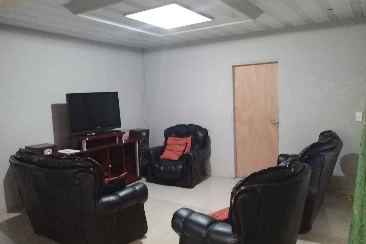 A living room featuring tiled flooring and a recessed ceiling design with a central light fixture.