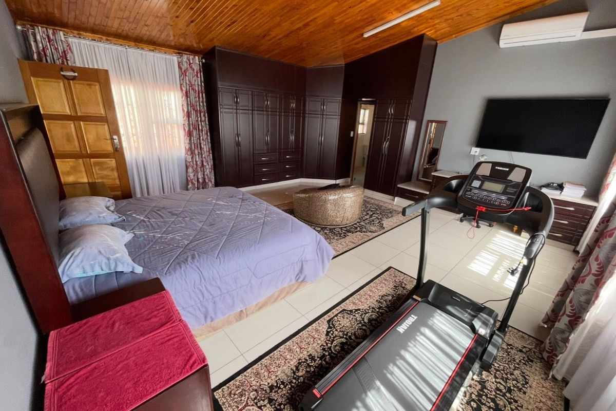 Spacious bedroom featuring extensive built-in cabinetry, a warm timber ceiling, tiled flooring, and an integrated air conditioning unit.