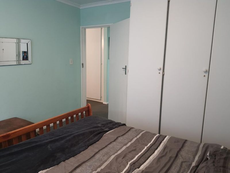 A bedroom featuring built-in wardrobes and access to an adjoining hallway.