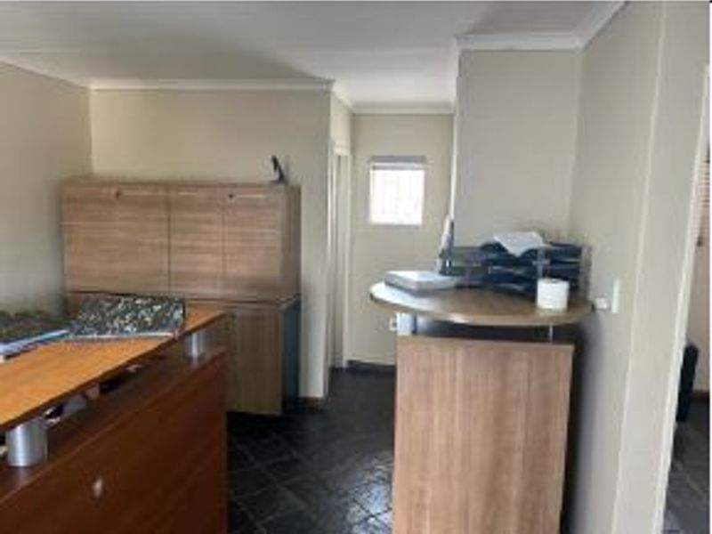 A functional office space featuring built-in cabinetry, tiled flooring, and neutral wall finishes, suitable for a professional work environment.