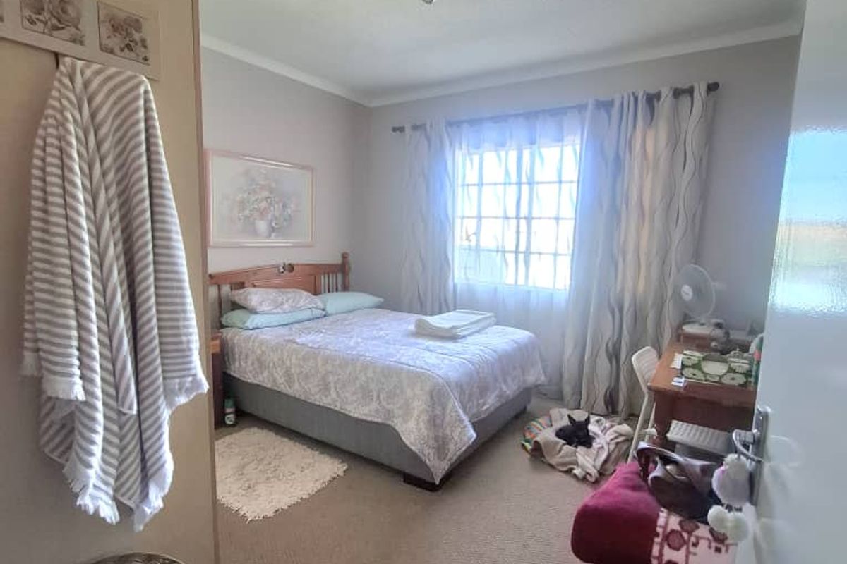 A standard bedroom featuring neutral wall tones, carpeted flooring, and a window with natural light, providing a comfortable and functional living space.