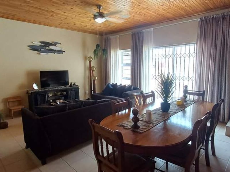 Open-plan living and dining area featuring a timber-clad ceiling, tiled flooring, and sliding door access to the exterior.
