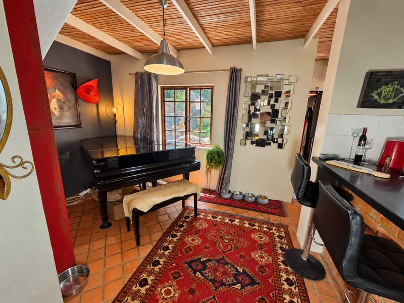 Open plan living area featuring exposed timber beam ceilings, terracotta floor tiles, and a breakfast bar connecting to the kitchen space.
