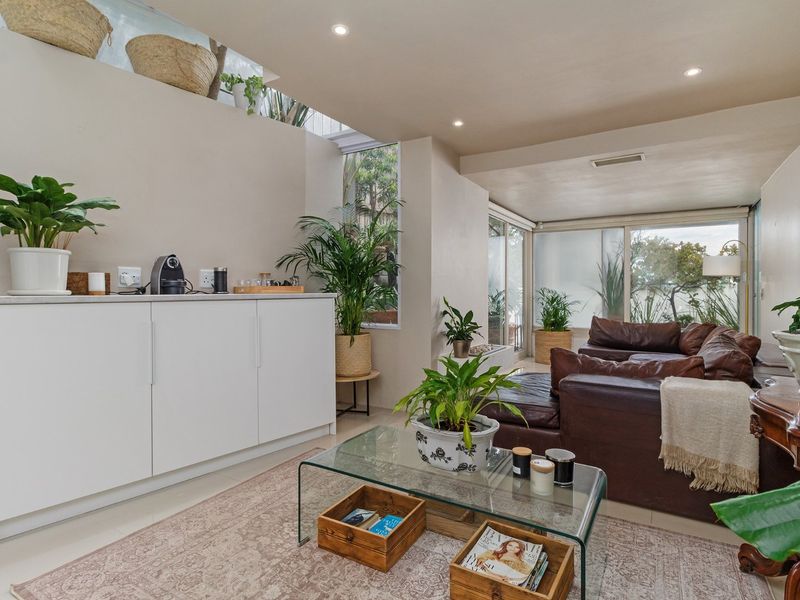 A bright living room featuring modern recessed lighting, built-in cabinetry, and large sliding glass doors that provide ample natural light and garden views.