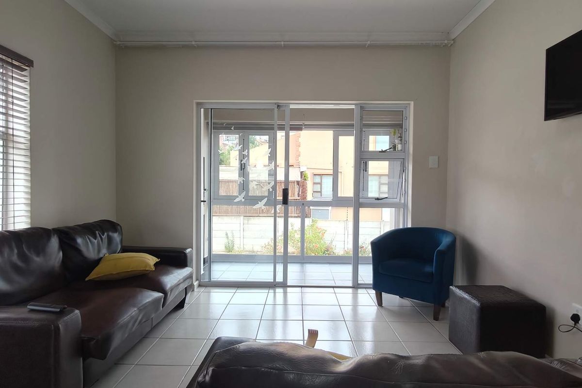 A living room featuring tiled flooring and a large sliding glass door that provides access to an outdoor patio area.