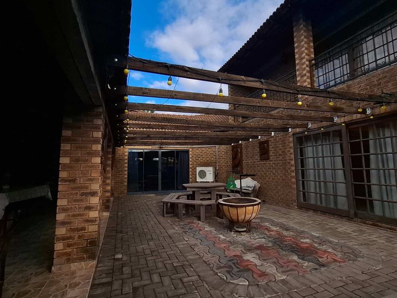 A spacious outdoor patio area featuring a timber pergola, brick construction, and paved flooring, providing a functional space for outdoor entertaining.