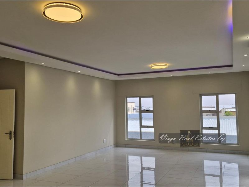 A spacious, modern living area featuring polished tiled floors, recessed ceiling lighting, and a split-system air conditioning unit.